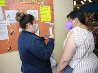 A nurse shows a new syringe to Person before before administering a   Covid-19 booster dose during a vaccination program in the local market...