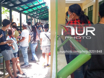 Filipinos wait in line to cast their votes for the 2022 national and local elections at polling precincts inside a school in Manila, Philipp...