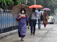 People carry umbrella during rainfall in Kolkata, India, 10 May, 2022. (