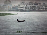 A boatman crosses the river Buriganga by boat during rain in Dhaka, Bangladesh on May 12, 2022. (
