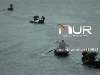 Passengers cross the river Buriganga by boat as they hold during rain in Dhaka, Bangladesh on May 12, 2022. (