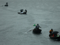 Passengers cross the river Buriganga by boat as they hold during rain in Dhaka, Bangladesh on May 12, 2022. (