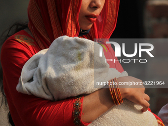 An Indian woman walks carrying a child covered with a towel to shield themselves from the sun on a hot summer day in New Delhi, India on May...