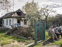 Local women sit on a​ bench near their house damaged during the Russian occupation of Zahaltsi village near Kyiv, Ukraine, ​May 13, 2022. (