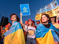 Fans of Ukraine's Kalush Orchestra pose with a Ukrainian flag and a sign in support of the Ukrainian situation ahead of the concert of the b...