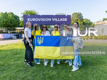 Fans of Ukraine's Kalush Orchestra pose with a Ukrainian flag and a sign ahead of their concert at Eurovision Village on May 11, 2022 in Tur...