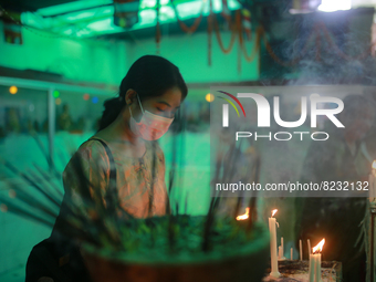 A Buddhist devotee lights candles at a temple during the Buddha Purnima festival in Dhaka, Bangladesh on May 15, 2022. (