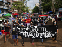Young demonstrators hold a banner as they march during an anti-coup protest in Yangon, Myanmar on May 16, 2022.
 (