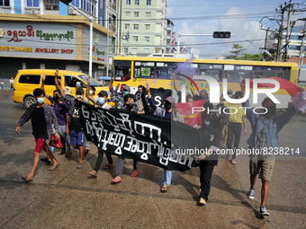 Young demonstrators hold banners and flags as they march during an anti-coup protest in Yangon, Myanmar on May 16, 2022. (