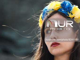 A Ukrainian woman with a crown of flowers in the colors of the Ukrainian flag takes part in the demonstration in Krakow, Poland on May 16, 2...