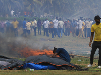 A Sri Lankan anti-government protester tries to retrieve belongings from his tent that is on fire as pro-government protesters look on after...