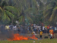 Sri Lankan pro-government protesters look on after setting fire to many tents belonged to anti-government protesters  at Gotagogama near the...