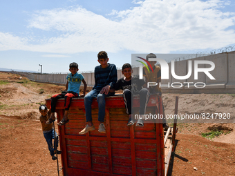 Camp children play on the wall separating Syria and Turkey near the town of Atma in Idlib countryside, northwest of Syria, on May 17, 2022....