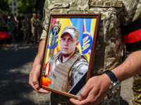 UZHHOROD, UKRAINE - MAY 16, 2022 - A serviceman holds a portrait during the farewell ceremony for Ukrainian defenders Oleksandr Serousov and...