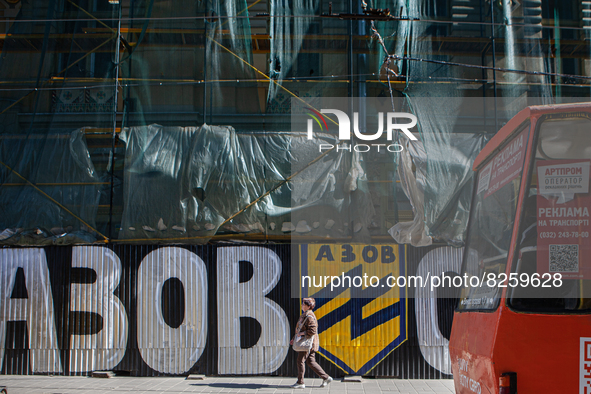 A woman walks by street art depicting the Azov Battalion symbol in Lviv on May 18, 2022. A controversial unit of the Ukrainian National Guar...