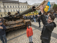 The bouquet of blue and yellow flowers sticking out in the barrel of the destroyed Russian tank displayed for Ukrainians to see at Mykhailiv...