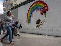 People are seen walking near a mural alluding to the fight against COVID-19, in the city downtown. Lisbon, May 23, 2022. Portugal is the Eur...