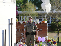 An officer is seen in front of the Robb Elementary School sign in Uvalde, Texas, May 25, 2022. (