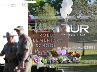 Officers walk past the Robb Elementary School sign in Uvalde, Texas, May 25, 2022. (
