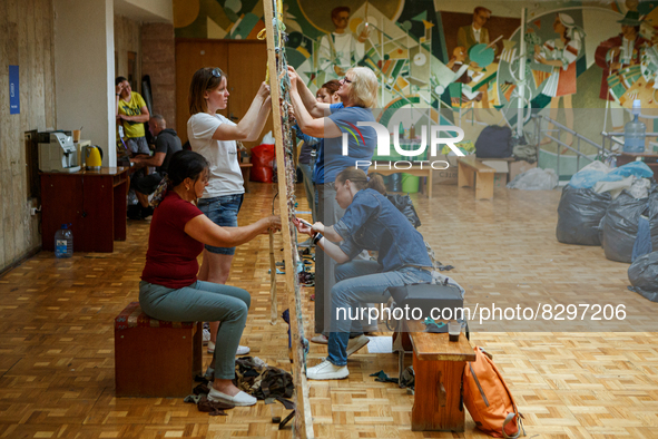 UZHHOROD, UKRAINE - MAY 25, 2022 - Volunteers weave camouflage nets for the Ukrainian military at the Padiiun Zakarpattia Regional Palace of...