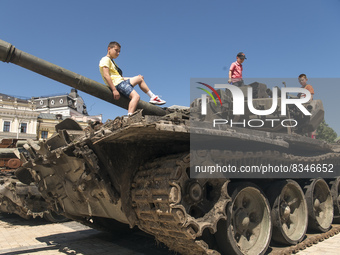 Teenagers play and pose for photography  on a burned Russian tank, displayed for Ukrainians to see at Mykhailivska Square in downtown Kyiv,...