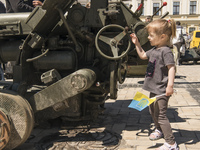 A child plays near destroyed Russian artillery cannon displayed for Ukrainians to see at Mykhailivska Square in downtown Kyiv, Ukraine, June...