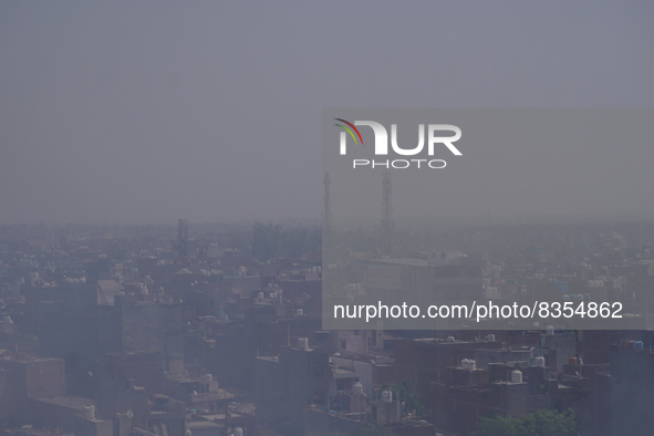 Residential buildings are seen enveloped in smoke as it billows from a burning garbage mound after a fire at the Bhalswa landfill site on Wo...