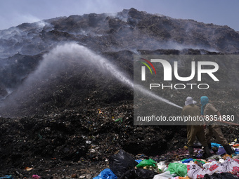 Firefighters try to douse fire as smoke billows from a burning garbage mound at the Bhalswa landfill site on World Environment Day in New De...