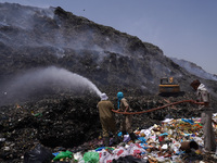 Firefighters try to douse fire as smoke billows from a burning garbage mound at the Bhalswa landfill site on World Environment Day in New De...