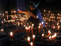 QUEZON CITY, Philippines - A woman lights a candle while carrying a wooden cross as she takes part at the Stations of the Cross inside a cha...