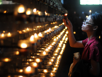QUEZON CITY, Philippines - A woman lights a candle after taking part at the Stations of the Cross inside a chapel in Quezon City, northeast...