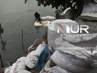 A worker cleans chemicals carrying plastic bags in the Buriganga River in Dhaka, Bangladesh on June 08, 2022. Buriganga river which flows by...
