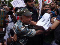 A security personnel tries to detin protestors during a demonstration alleging targeted demolition drive against Muslims following clashes l...