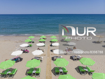 Aerial images from a drone of the coast of Rethymno town with the long beach and the beach bars in Creta island. People are seen enjoying th...