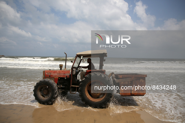 A Palestinian man drives a tractor on the shore of the Mediterranean Sea in Gaza City, June 22, 2022. 