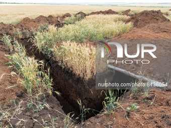 An empty trench is seen in the fields near the village of Temyrivs'ka, Ukraine, on june 22, 2022.(