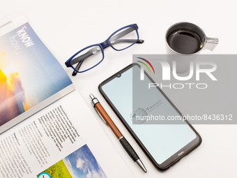 In this photo illustration a Wikipedia logo seen displayed on a smartphone screen on a desk next to a cafe, a pen, glasses and a magazine in...