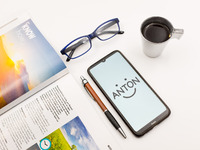 In this photo illustration an Anton logo seen displayed on a smartphone screen on a desk next to a cafe, a pen, glasses and a magazine in At...