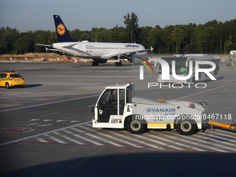 Airport vehicles and an airplane are seen at the airport in Balice near Krakow, Poland on June 27, 2022. (