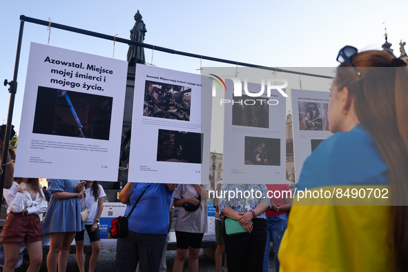 People are watching pictures by Azov soldier-photographer Dmytro 'Orest' Kozatsky, shown on outdoor temporary exhibition titled 'Azovstal -...