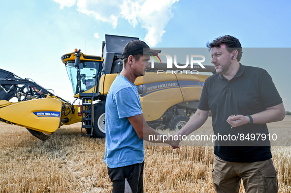 ZAPORIZHZHIA REGION, UKRAINE - JULY 05, 2022 - Head of the Zaporizhzhia RMA Oleksandr Starukh shakes hands with a harvester operator in the...