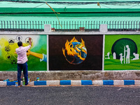 An artist is seen painting environmental awareness wall art at entrance of a government school in Kolkata , India , on 6 July 2022 . (