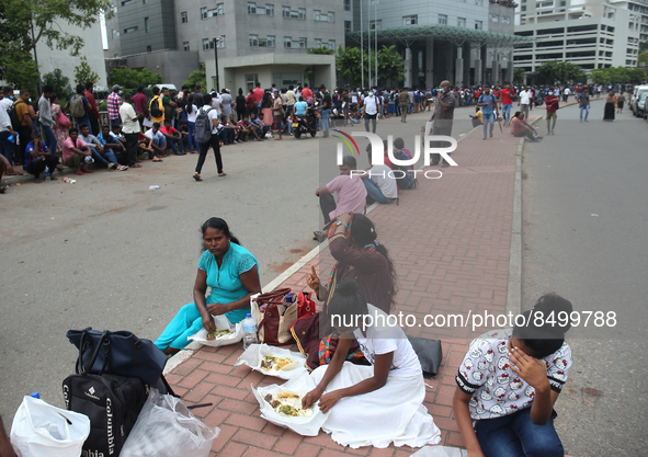 People eat food, as they wait to apply for passports at the Sri Lanka Immigration and Immigration Department in Colombo, Sri Lanka, on July...