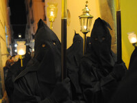 Hooded Penitents of the Arciconfraternita of Servi di Maria carry crosses and torches as they take part in Good Friday procession long the s...