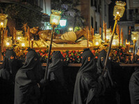 Hooded Penitents of the Arciconfraternita of Servi di Maria carry crosses and torches as they take part in Good Friday procession long the s...
