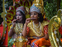 Children, dressed as Hindu god Krishna (left) and Arjuna, one of the protagonists in the ancient Indian epic called Mahabharata (right), eat...