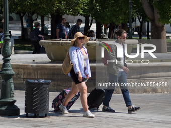 Tourists are walking holding suitcases at Syntagma square during high temperatures in Athens, Greece on July 17, 2022. (