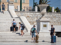 Tourists are walking holding suitcases at Syntagma square during high temperatures in Athens, Greece on July 17, 2022. (