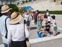 Tourists are watching the changing of the guard at Syntagma square front of the Greek Parliament during high temperatures in Athens, Greece...