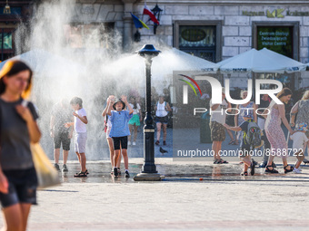 Tourists are cooling by a water sprinkler at the Main Square in Krakow, Poland on July 25, 2022. Hot air masses from over Africa covered mos...